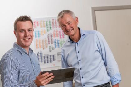 Benjamin og Michael fra COOP Spotmarket To mænd kigger står med tablet foran plakat med Verdensmålene